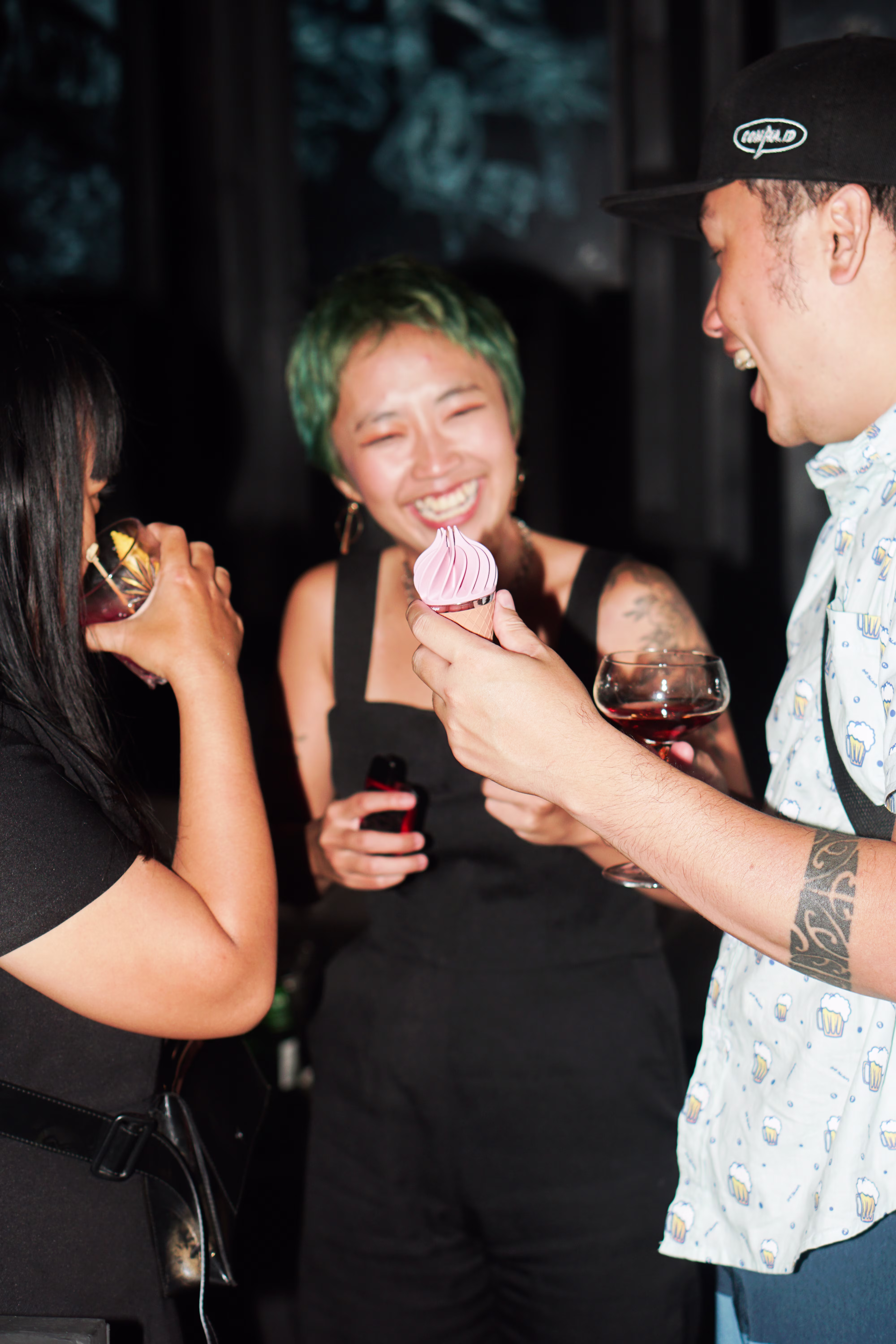 An excited attendee smiling as a guest displays an ice cream cone-shaped vibrator from Laciasmara at the Asmaradoor Tingle and Mingle Party at Joshua District