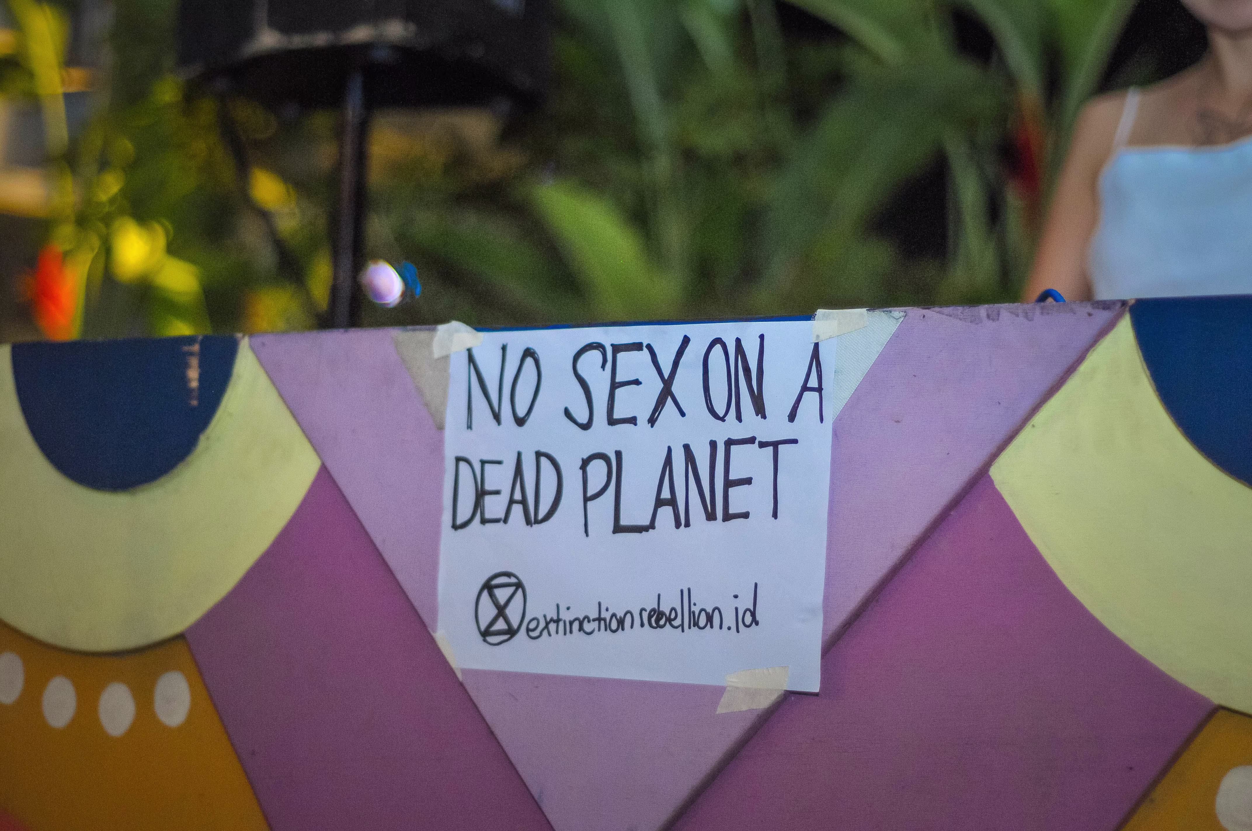 A close-up of a sign on the DJ booth reading 'NO SEX ON A DEAD PLANET' during the Laciasmara 7th anniversary celebration at ¡Porqué No!