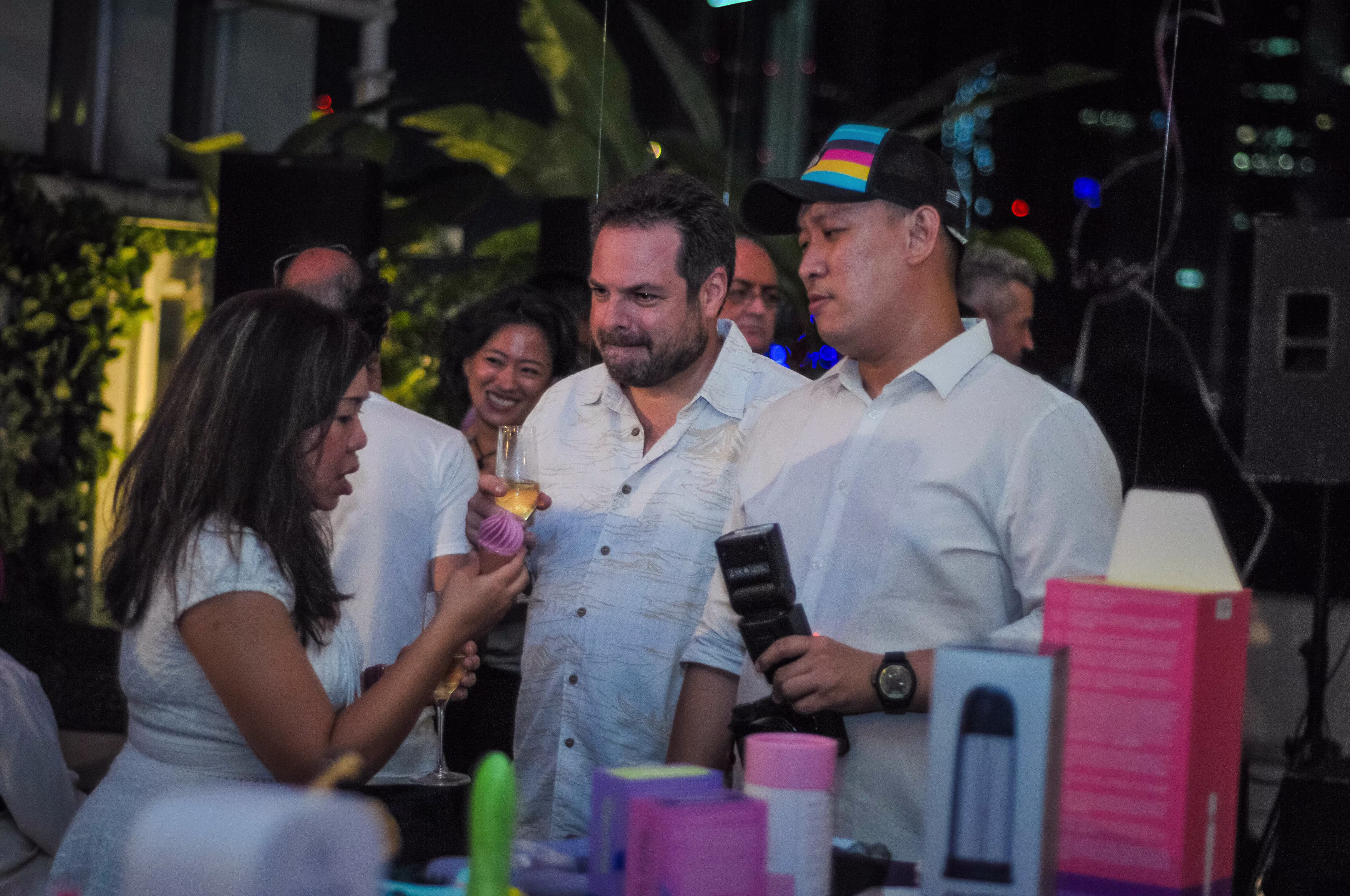 A group of party guests smiling while testing the ice cream cone-shaped novelty vibrator at the Teman Asmara Bersua gathering