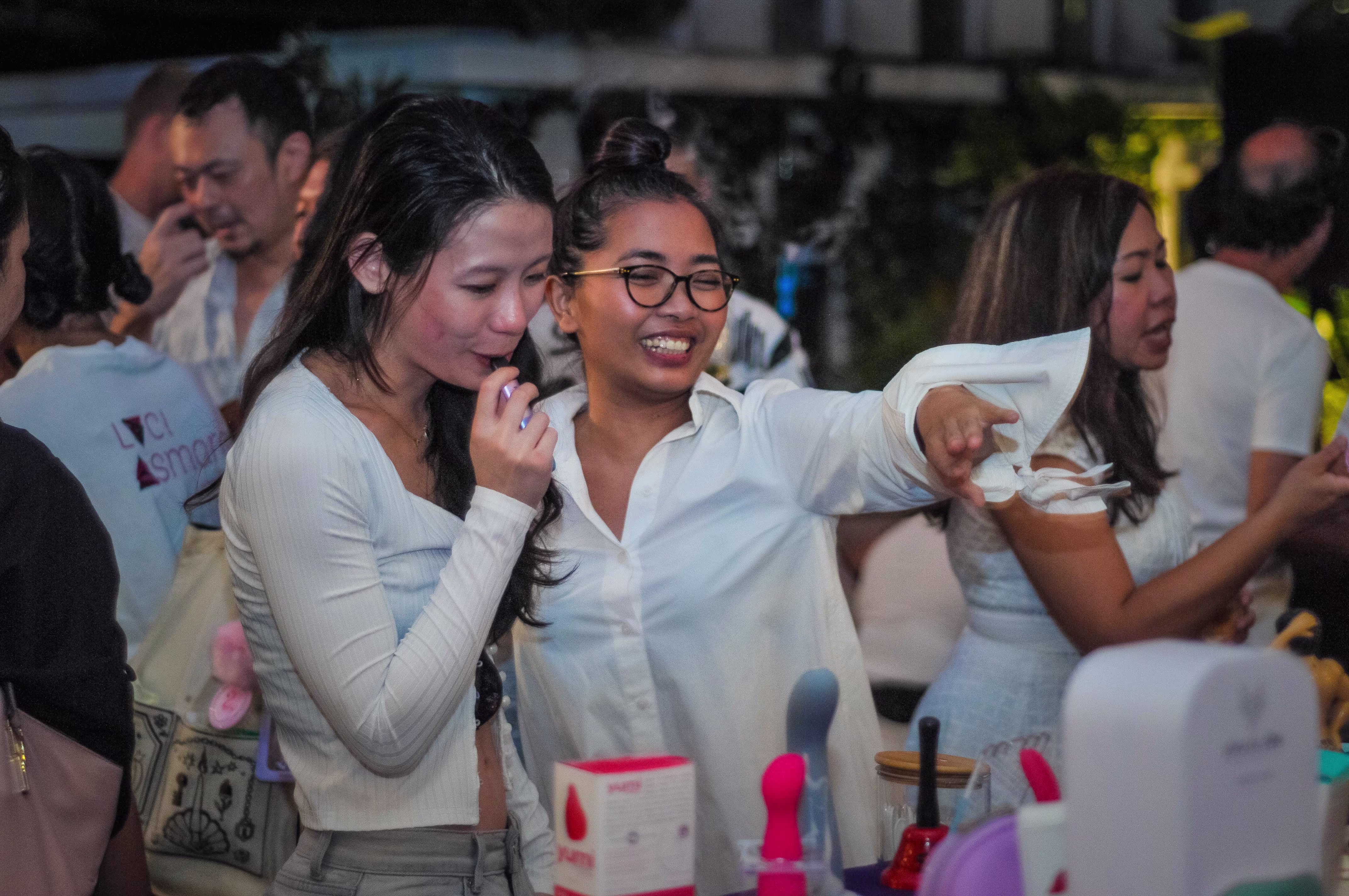 Two women engaged in a casual discussion about the intimate wellness products showcased on the display table