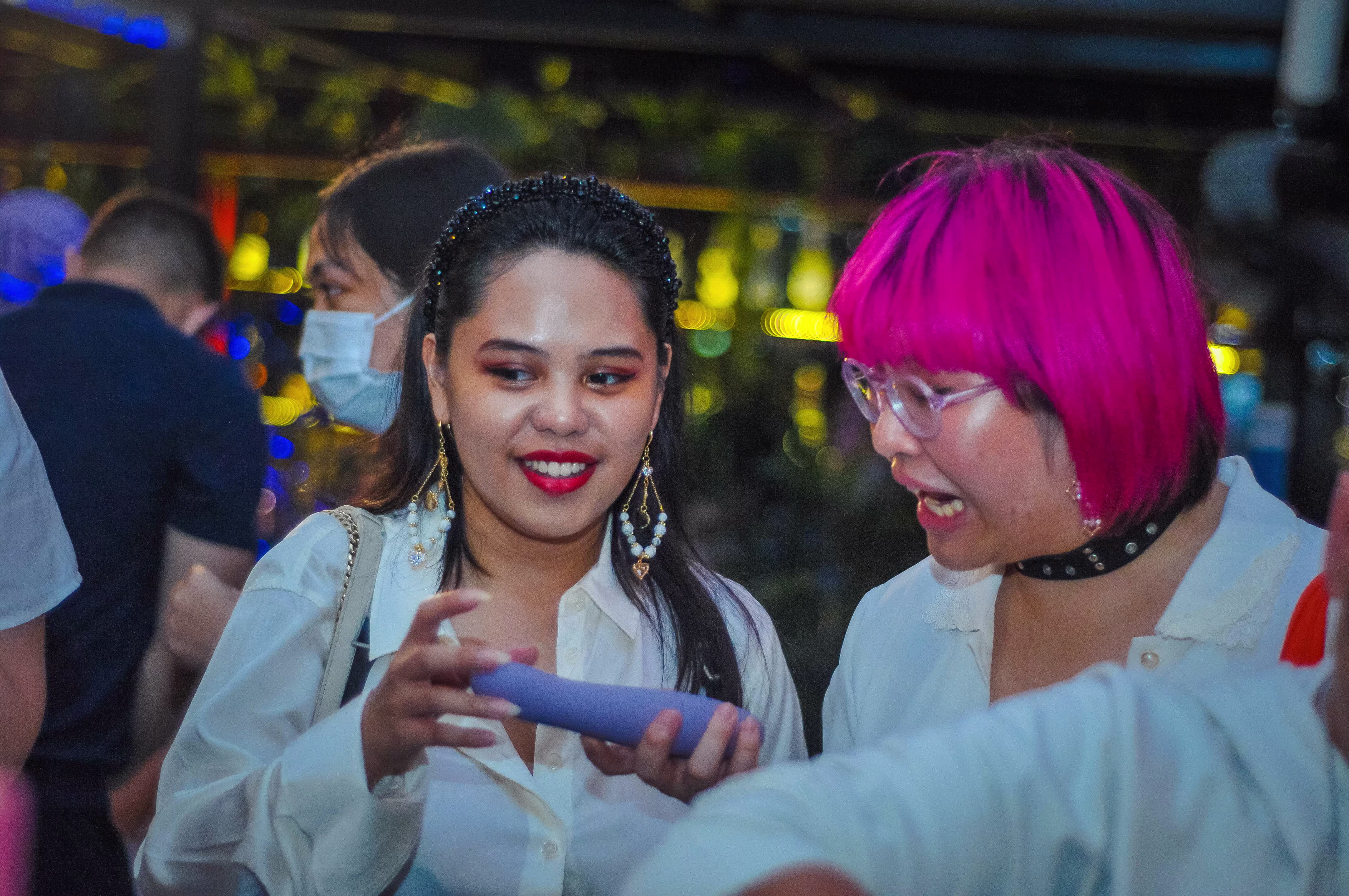 Two female attendees exchanging thoughts and learning about a wellness vibrator product at the Teman Asmara Bersua party