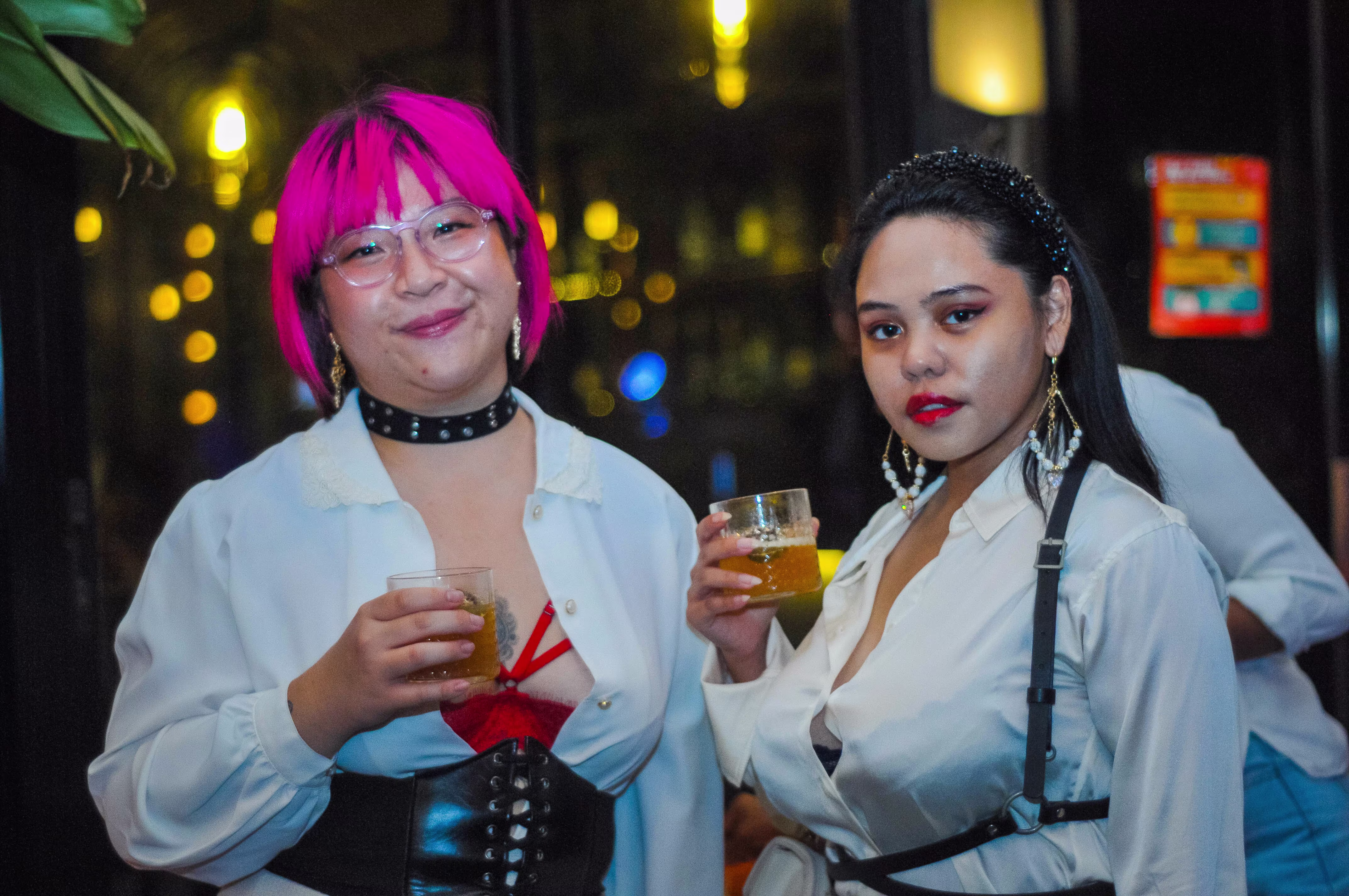 Two female guests smiling and posing together with their drinks on the ¡Porqué No! rooftop during the Laciasmara celebration