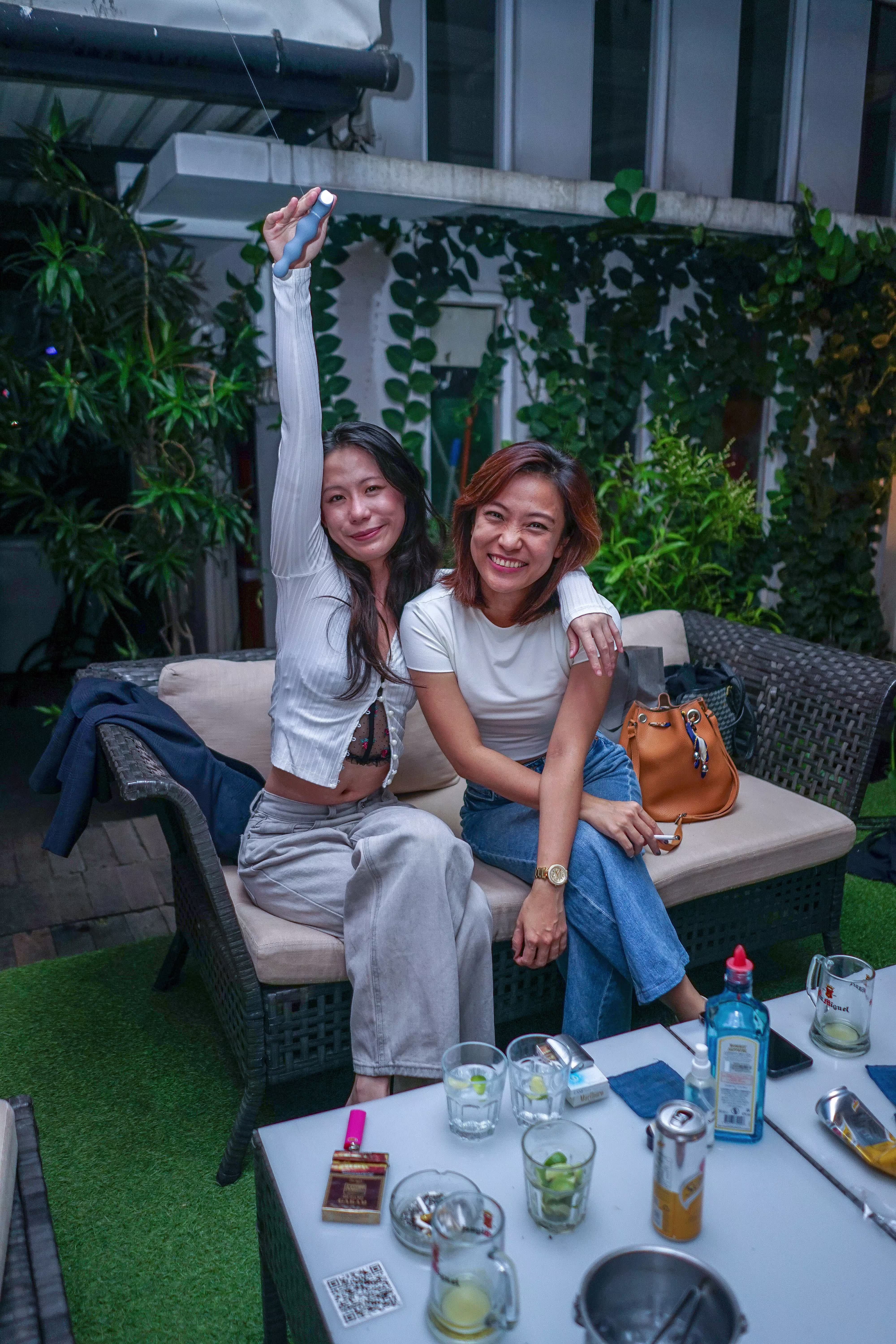 Two happy female guests smiling for a photo, with one lifting a Laciasmara vibrator in her hand to celebrate