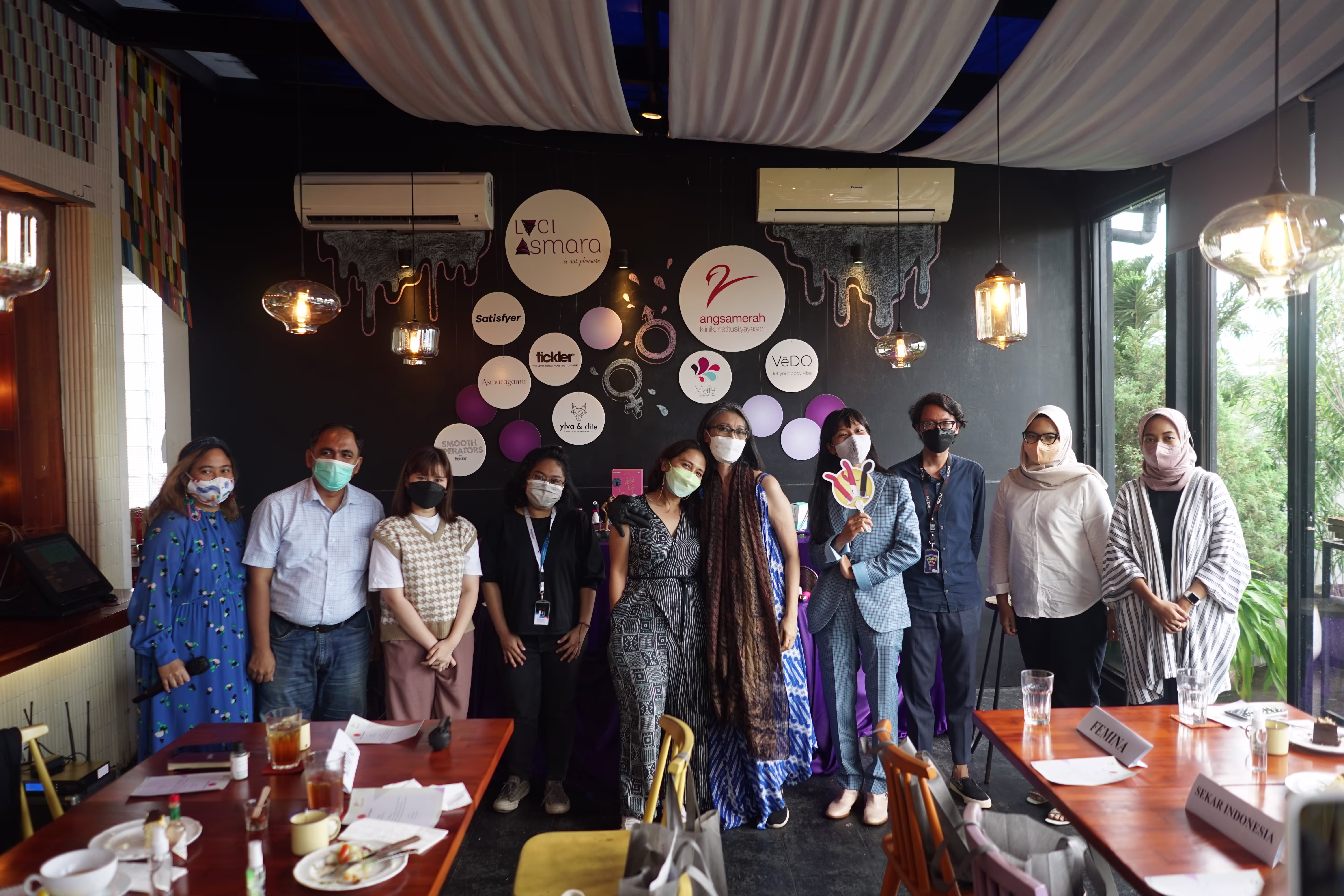 A group photo of attendees and speakers posing together in front of the main Laciasmara and Angsa Merah Klinik product display