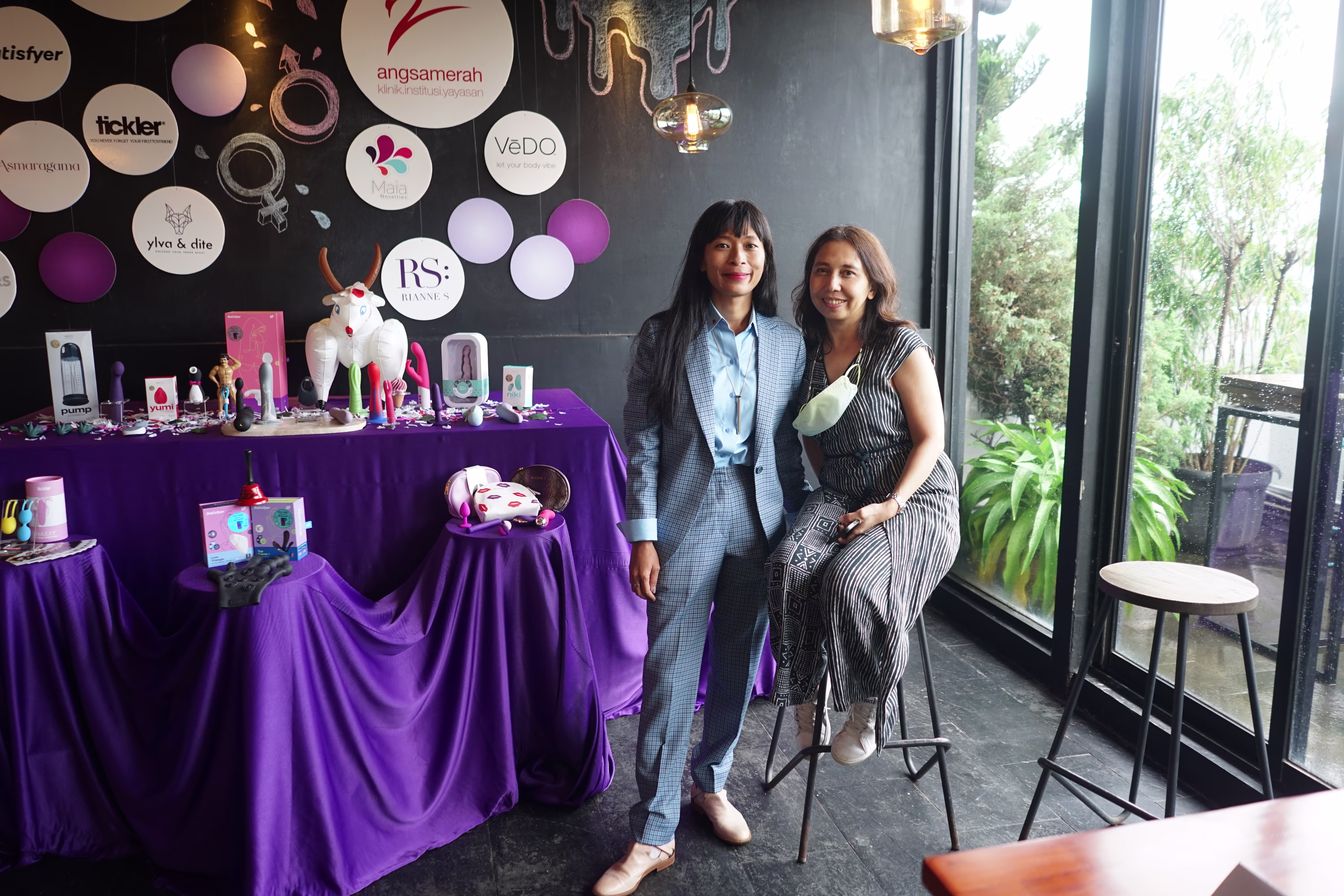 Laciasmara founder Rendra Susanti and a guest posing with warm smiles next to the sexual wellness exhibition table