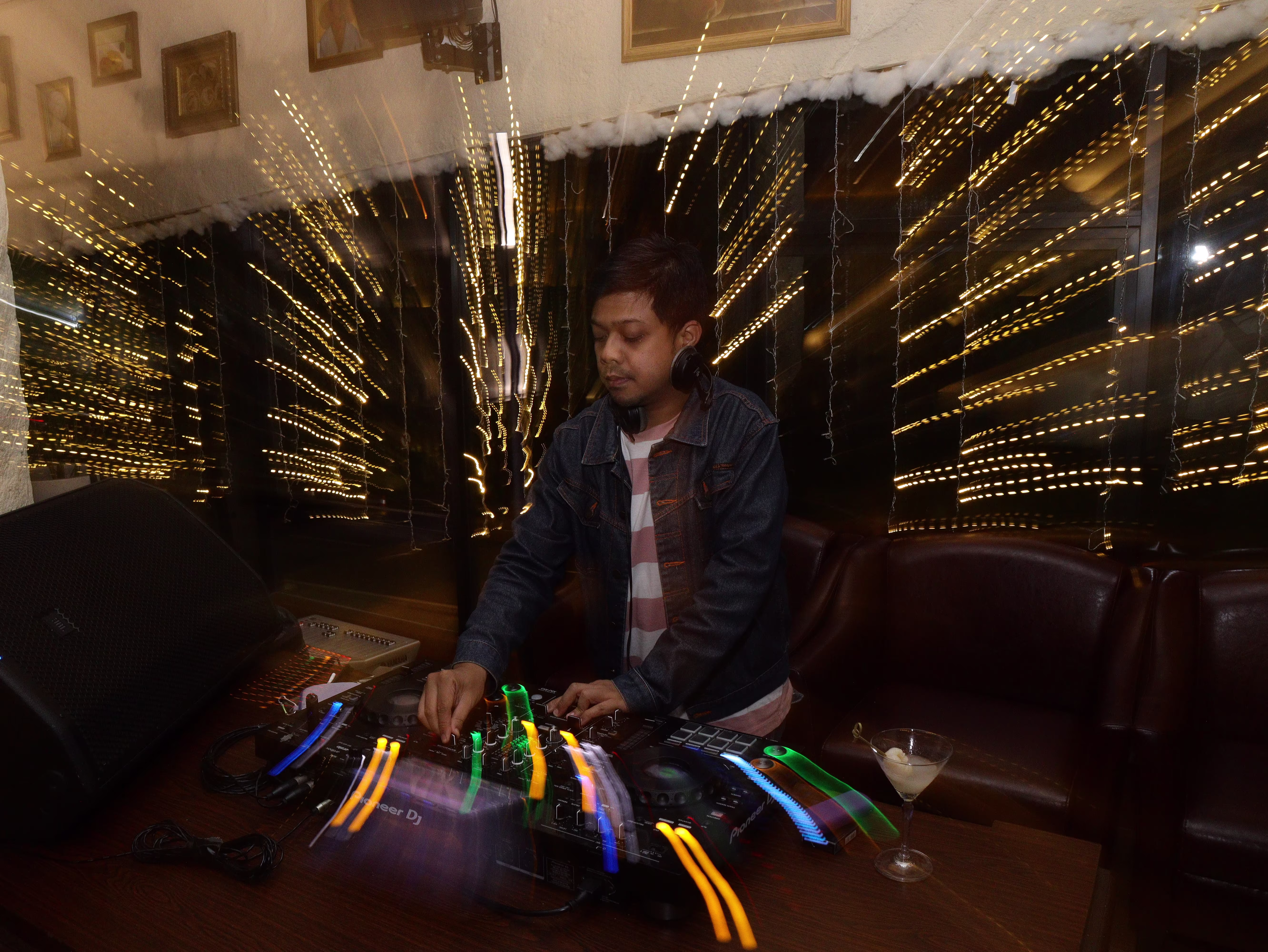 A DJ playing music at Dasa Asmara Bersua, surrounded by a heavy motion blur and stretched, blurry light streaks.