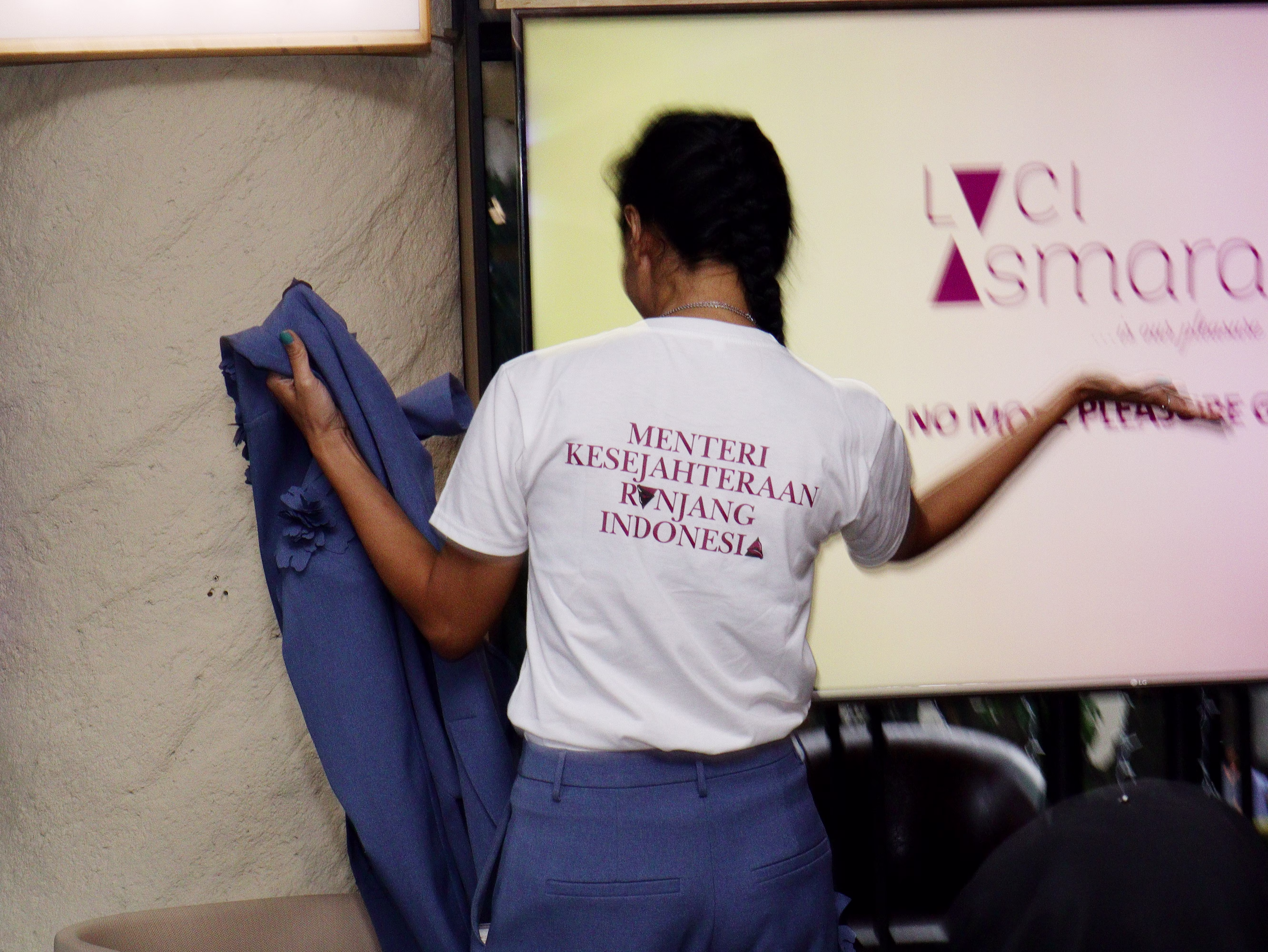 Rendra Susanti on stage at Dasa Asmara Bersua, showing the back of her outfit which reads 'Menteri Kesejahteraan Ranjang Indonesia'.